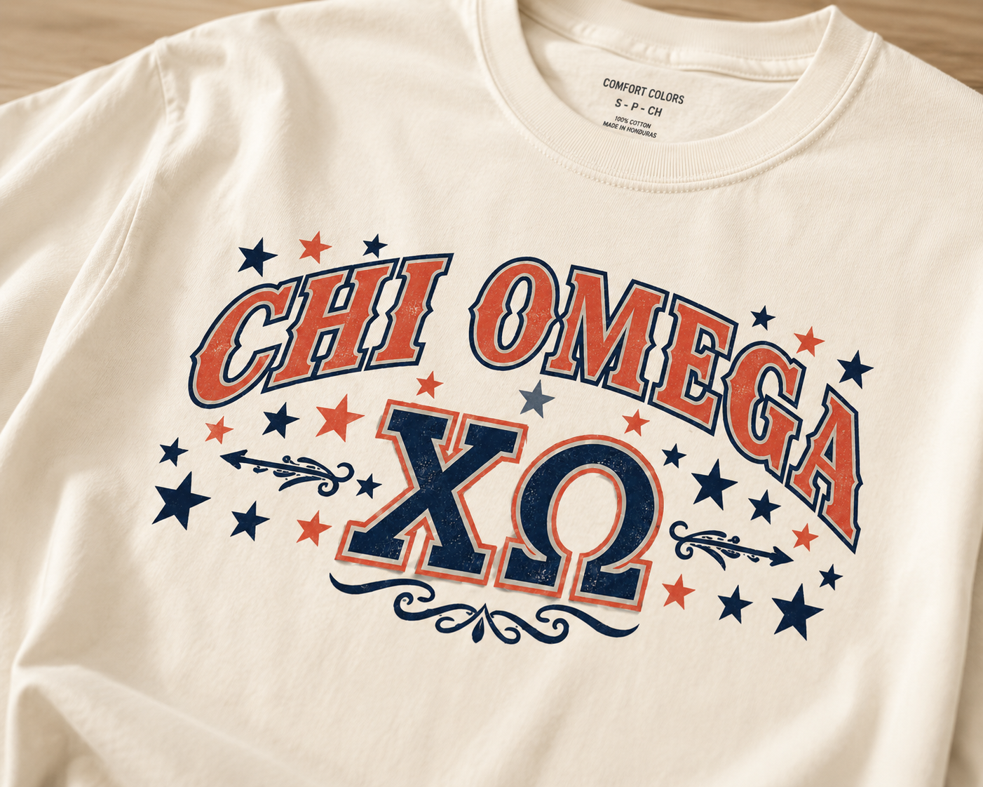 Close-up of red and navy Chi Omega collegiate artwork printed on a cream T-shirt